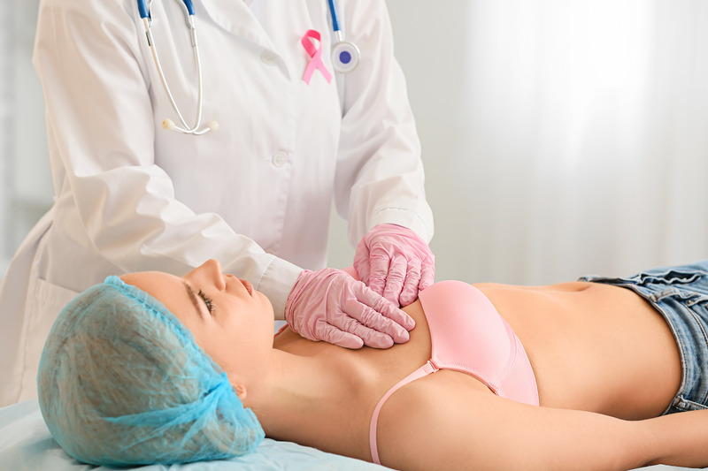 Mammologist examining young woman in clinic. Breast cancer awareness
